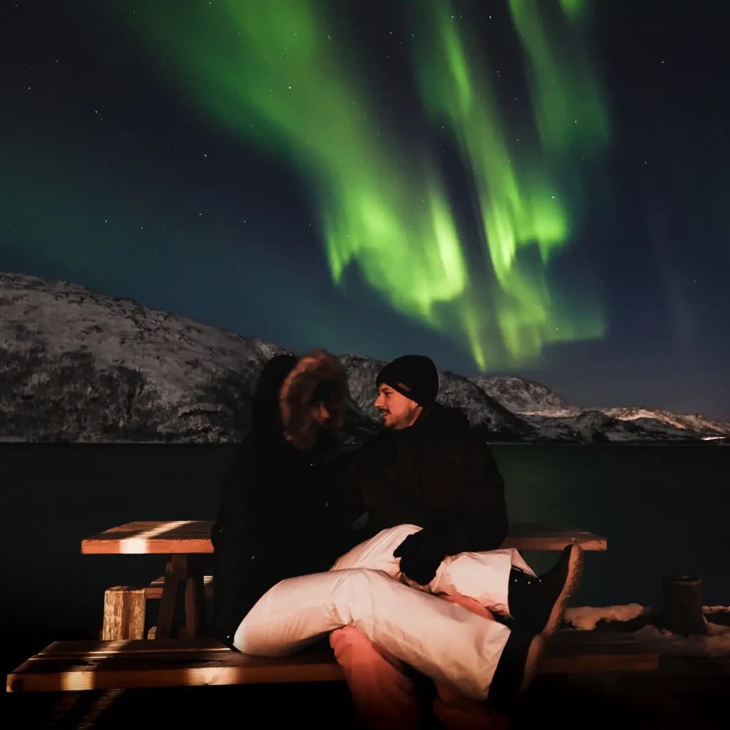 Fotograferen noorderlicht met personen op voorgrond aan fjord in Tromsø