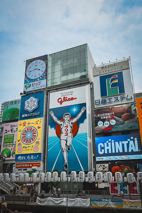 De iconische Glico Running Man in Dotonbori, Osaka, omringd door kleurrijke reclameborden.