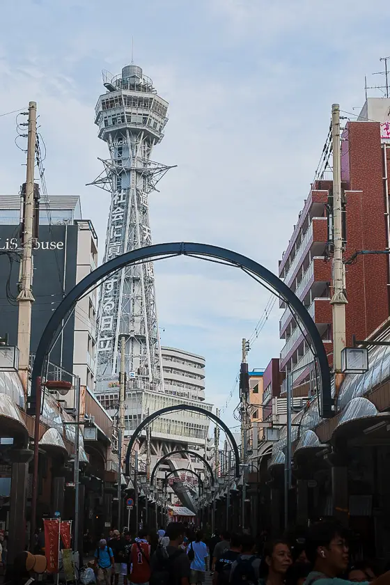 Zicht op Tsutenkaku-toren vanuit een drukke winkelstraat in Shinsekai, Osaka.