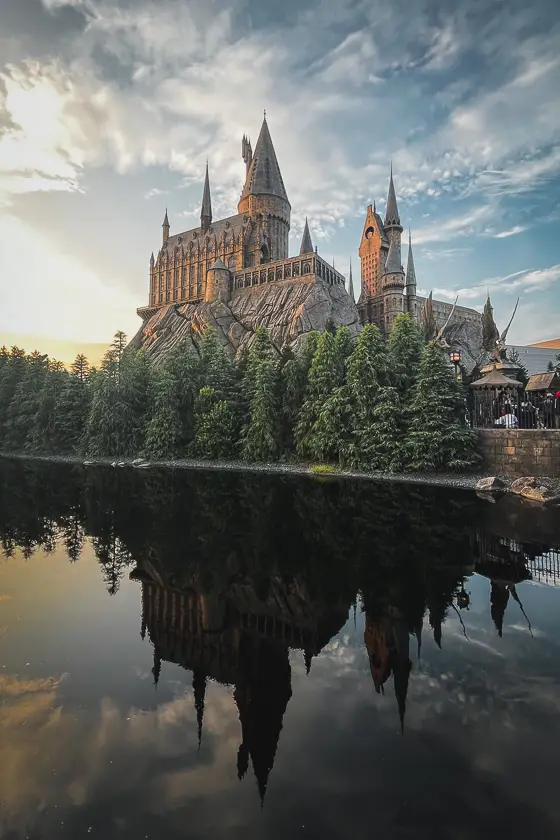 Hogwarts-kasteel in Universal Studios Japan bij zonsondergang, met prachtige reflectie in het water.