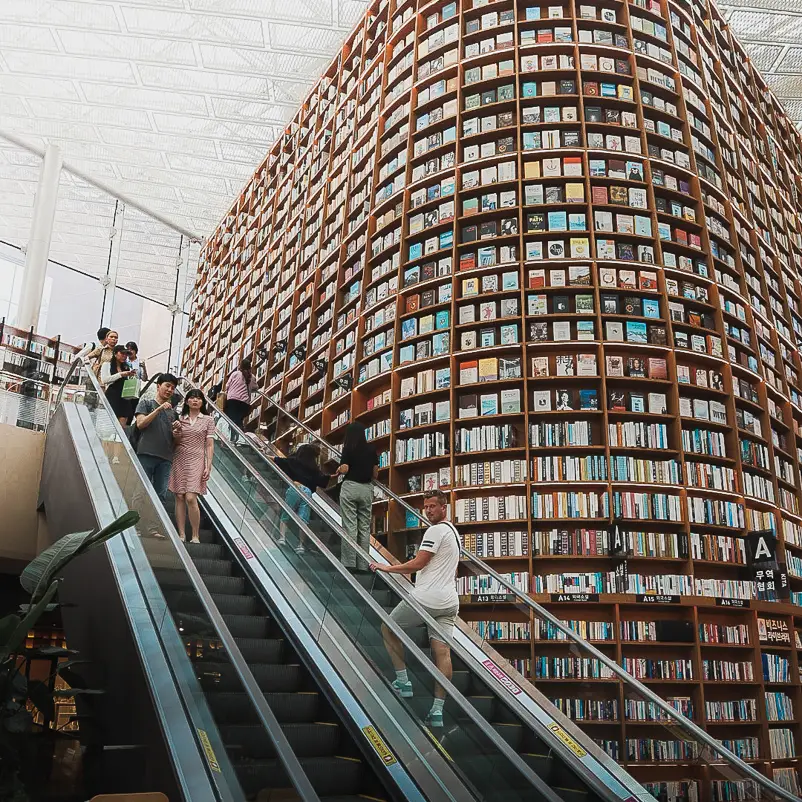 Reizigers op de roltrap voor de gigantische boekenwand in de Starfield Library in COEX Mall in Seoul
