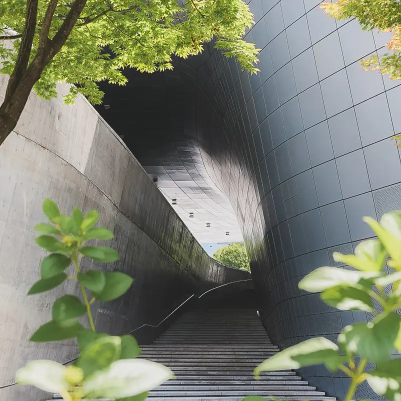 Smalle doorgang met trappen tussen de gebogen metalen wanden van de DDP in Seoul