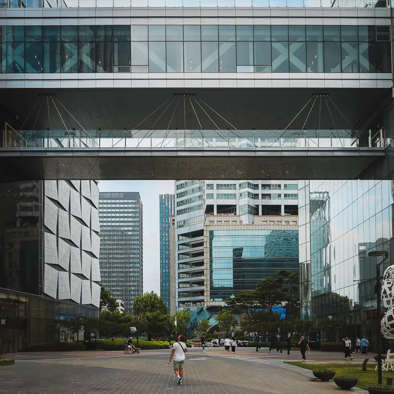 Reiziger wandelt onder de skybridge tussen moderne kantoorgebouwen in het COEX district in Gangnam