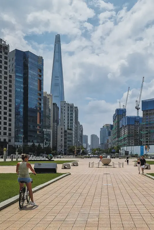 Reiziger fietst richting de Lotte World Tower in Seoul tussen moderne wolkenkrabbers