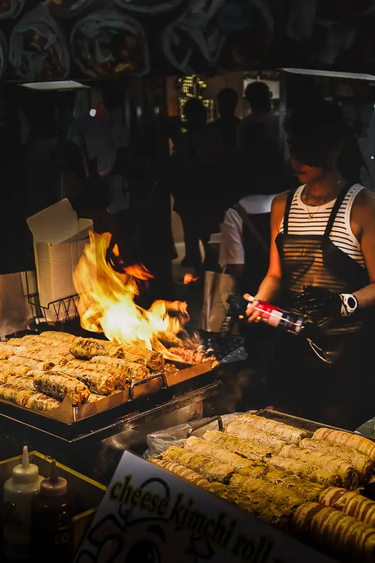 Streetfoodkraam in Myeongdong waar kaas–kimchi rolls op de grill met open vuur worden bereid