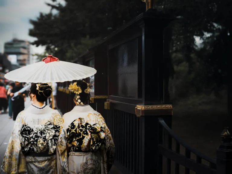 Twee vrouwen in traditionele kimono wandelen door een straat in Tokyo met een Japanse parasol